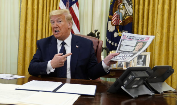 President Donald Trump holds up a copy of the New York Post as he speaks before signing an executiv...