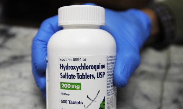 FILE - In this April 6, 2020 file photo, a pharmacist holds a bottle of the drug hydroxychloroquine...
