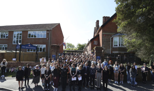 Colleagues and pupils of teacher James Furlong stand together to take part in a period of silence a...