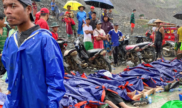 People gather near the bodies of victims of a landslide near a jade mining area in Hpakant, Kachine...