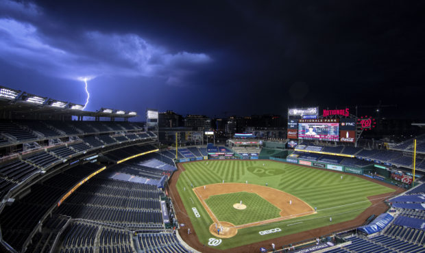 A bolt of lightning comes down from the clouds during the sixth inning of an opening day baseball g...