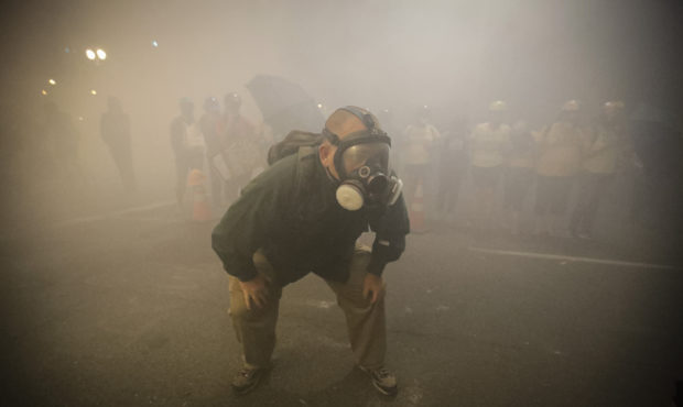 A demonstrator wears a gas mask as federal officers deploy tear gas during a Black Lives Matter pro...