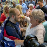 FILE: In this May 28, 2018, file photo, Josh Holt, left, is draped in an American flag by his grandmother, Linda Holt, upon returning to Salt Lake City. Holt spent nearly two years in prison in Venezuela with his wife, Thamy, on what the US government said were false charges that never resulted in a trial. (AP Photo/Kim Raff, File)