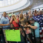 FILE: Friends and family react Monday, May 28, 2018, as Josh Holt and his family arrive in Salt Lake City after receiving medical care and visiting President Donald Trump in Washington. Josh and Thamy Holt were locked in a Caracas jail alongside some of the Venezuela's most-hardened criminals - and President Nicolas Maduro's top opponents - for what the U.S. government argued were bogus charges of stockpiling weapons. (AP Photo/Kim Raff)