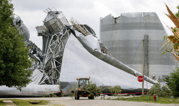Iowa Department of Transportation workers help with tree debris removal as grain bins from the Arch...