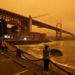 People stop at Fort Point to take morning pictures of the Golden Gate Bridge covered in smoke from wildfires Wednesday, Sept. 9, 2020, in San Francisco. (AP Photo/Eric Risberg)