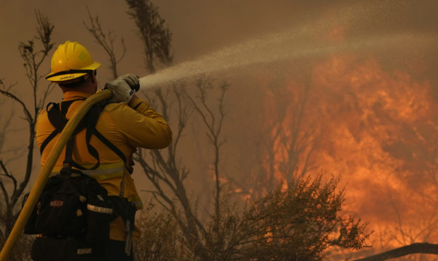 Jesse Vasquez, of the San Bernardino County Fire Department, hoses down hot spots from the Bobcat F...