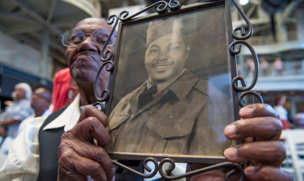 World War II veteran Lawrence Brooks holds a photo of him from 1943 as he celebrates his 110th birt...