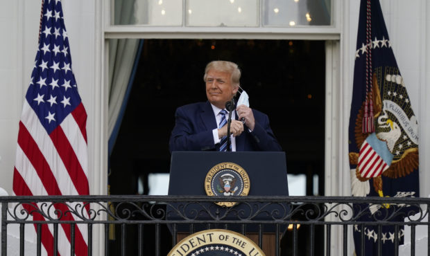 President Donald Trump removes his face mask to speak from the Blue Room Balcony of the White House...