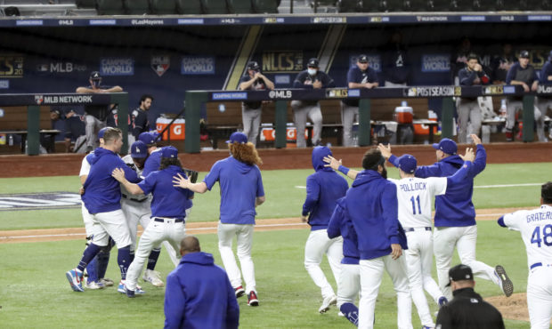 Los Angeles Dodgers players mob relief pitcher Julio Urias after the final out as they defeat the A...