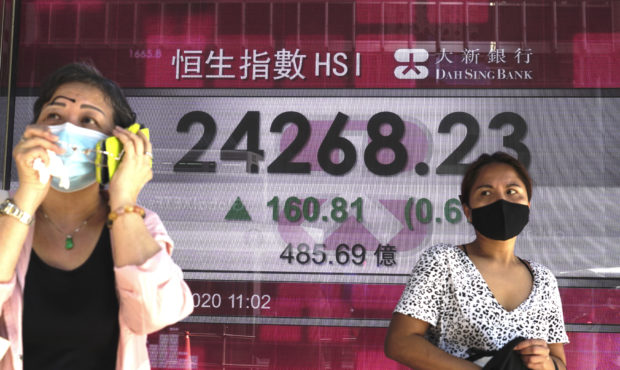 People walk past a bank's electronic board showing the Hong Kong share index at Hong Kong Stock Exc...