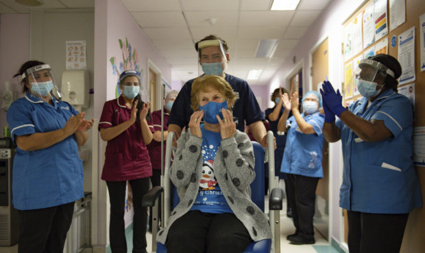 Margaret Keenan, 90, is applauded by staff as she returns to her ward after becoming the first pati...