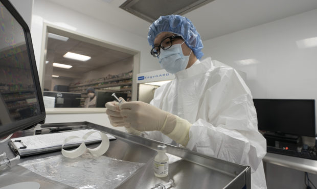 A pharmacist labels syringes in a clean room where doses of COVID-19 vaccines will be handled, Wedn...