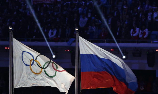 FILE - In this Feb. 23, 2014 file photo the Russian national flag, right, flies after it is hoisted...