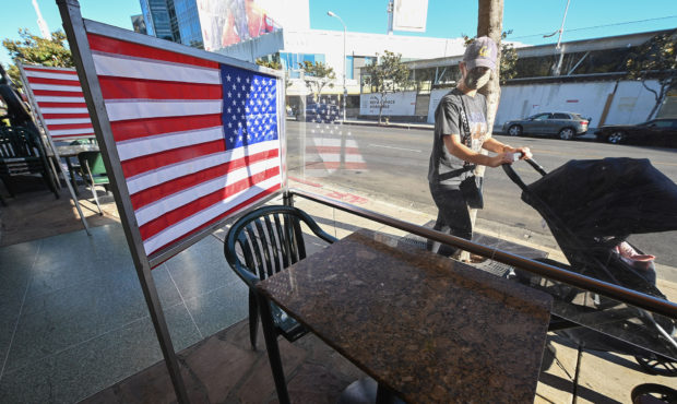Empty patio tables separated by plastic dividers adorned with American flags are seen at Mel's driv...