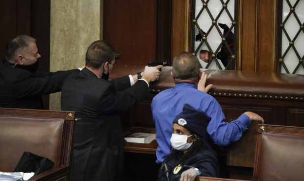 Police with guns drawn watch as protesters try to break into the House Chamber at the U.S. Capitol ...