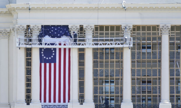 Workers install a flag on the West Front of the U.S. Capitol as preparations take place for Preside...