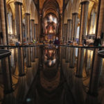 People are reflected in the 'Refection Pool' inside Salisbury Cathedral in Salisbury, England, Wednesday, Jan. 20, 2021, as they leave after receiving their Pfizer-BioNTech vaccination. Salisbury Cathedral opened its doors for the second time as a venue for the Sarum South Primary Care Network COVID-19 Local Vaccination Service. (AP Photo/Frank Augstein)