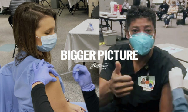 This image provided by Budweiser shows two health care workers getting vaccinated in an advertiseme...
