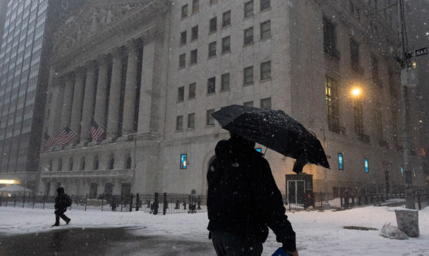 A man walks past the New York Stock Exchange during a snowstorm, Monday, Feb. 1, 2021, in New York....