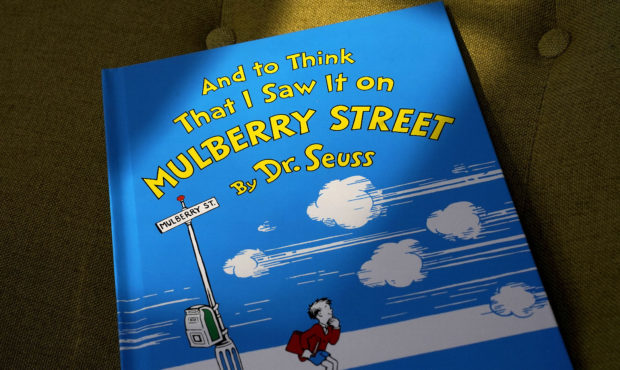 A copy of the book "And to Think That I Saw It on Mulberry Street," by Dr. Seuss, rests in a chair,...