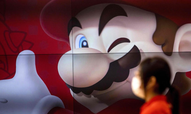 An employee stands next to a screen displaying Nintendo game character Mario at a Nintendo store in...