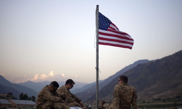 FILE - In this Sept. 11, 2011 file photo, US soldiers sit beneath an American flag just raised to c...