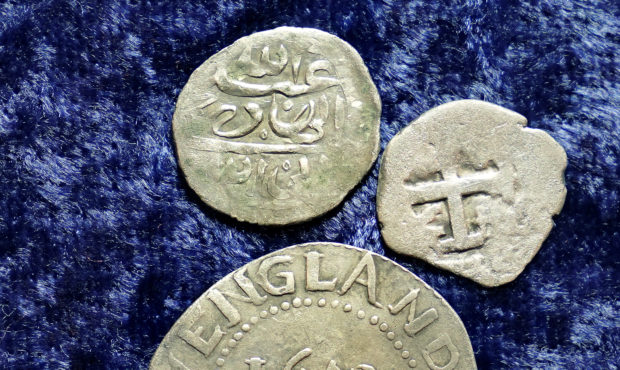 A 17th century Arabian silver coin, top, that research shows was struck in 1693 in Yemen, rests nea...