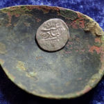 A 17th century Arabian silver coin that research shows was struck in 1693 in Yemen, rests in a 17th century brass spoon on a table, in Warwick, R.I., Thursday, March 11, 2021. The coin was found at a farm, in Middletown, R.I., in 2014 by metal detectorist Jim Bailey, who contends it was plundered in 1695 by English pirate Henry Every from Muslim pilgrims sailing home to India after a pilgrimage to Mecca. (AP Photo/Steven Senne)