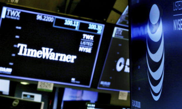 FILE - In this June 13, 2018, file photo, the logos for Time Warner and AT&T appear above alter...