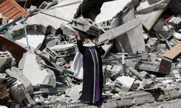 A woman reacts while standing near the rubble of a building that was destroyed by an Israeli airstr...
