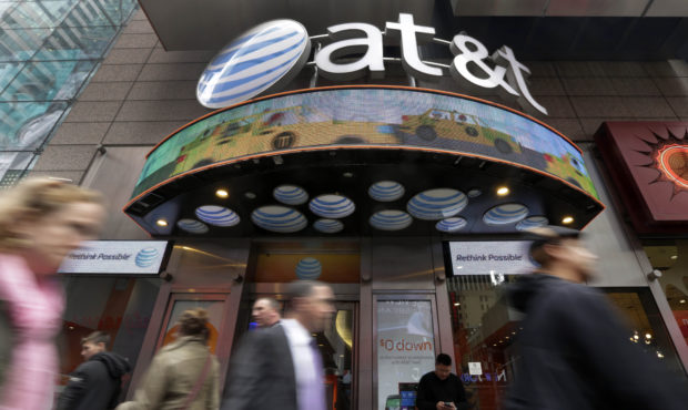 FILE - In this Oct. 21, 2014 file photo, people pass an AT&T store in New York's Times Square. ...