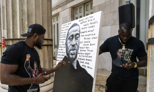 Artist Dennis Owes, 31, from Ghana gives the last touch to his portrait of George Floyd during a ra...