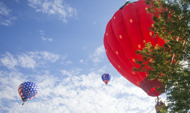 Three hot air balloons — including Strawberry Heights, right, start to land on the second day of ...