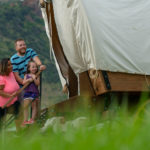 A family looks into a wagon camper at East Canyon State Park Utah State Parks