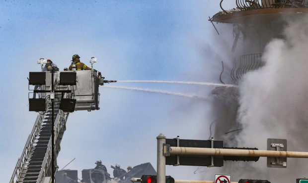 Firefighters battle a blaze as rescue workers search debris at the 12-story oceanfront condo, Champ...