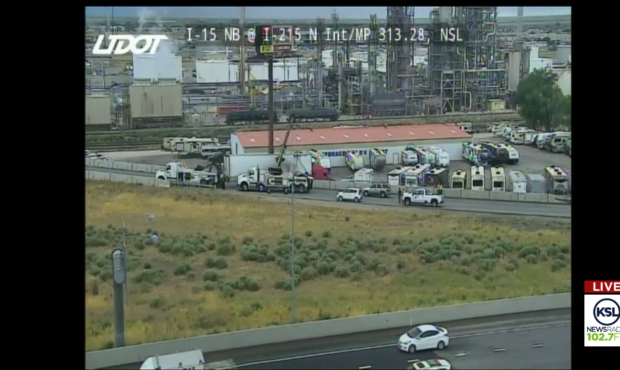 A semi high centered on a barrier of the ramp between SB I-15 and WB I-215.

UDOT...
