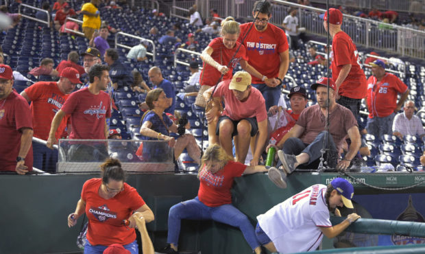 Fans jump into a camera well after hearing gunfire from outside the stadium, during a baseball game...