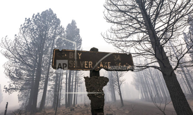 A sign damaged by the Bootleg Fire stands among the haze on Thursday, July 22, 2021, near Paisley, ...
