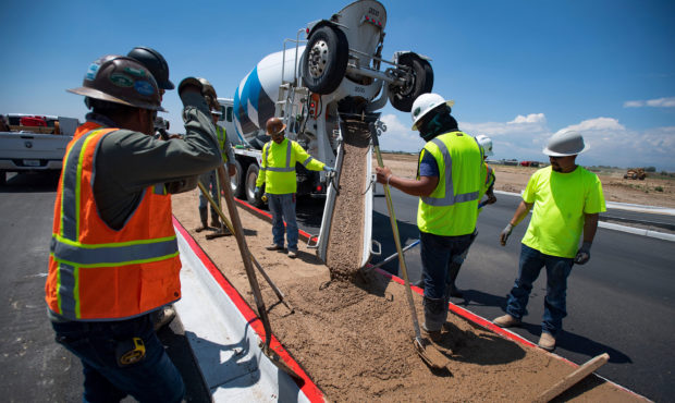 Construction workers pour concrete into a median along Larimer County Road 5 near Windsor, Colo. on...