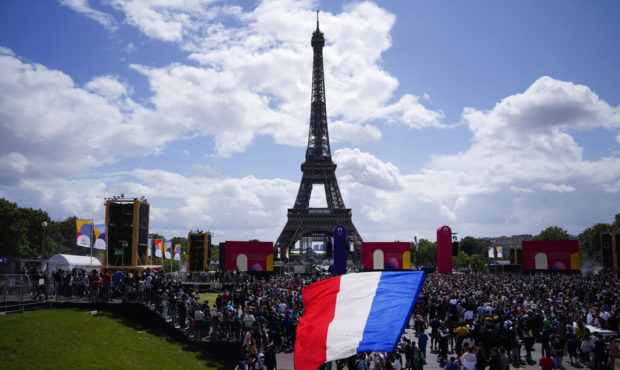 A man unfurls a French flag at the Olympics fan zone at Trocadero Gardens in front of the Eiffel To...