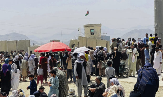 people are pictured gathered outside of an airport in Kabul...