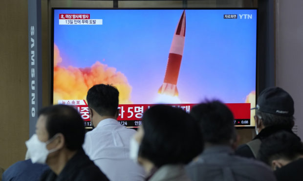 People watch a TV showing a file image of North Korea's missile launch during a news program at the...
