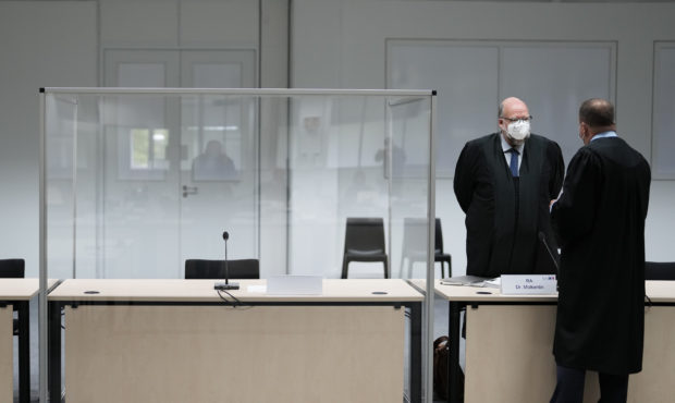 Two lawmakers stand next to an empty seat of the accused at the courtroom, prior to a trial against...