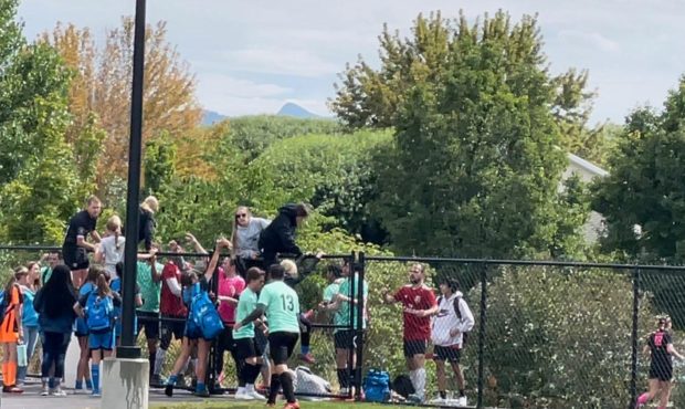 Players and parents scale and jump a fence after parents say a gun was pulled during an argument at...