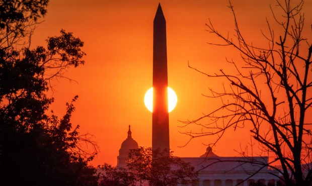 The sun rises behind the Washington Monument on the last day of summer in Washington, Monday, Sept....