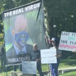 Anti-vaccine demonstrators hold a large banner with a photo of Utah Gov. Spencer Cox referring to him as "the real virus" during a demonstration at the Governor's Mansion in Salt Lake City on Oct 3, 2021(Bri Bright)
