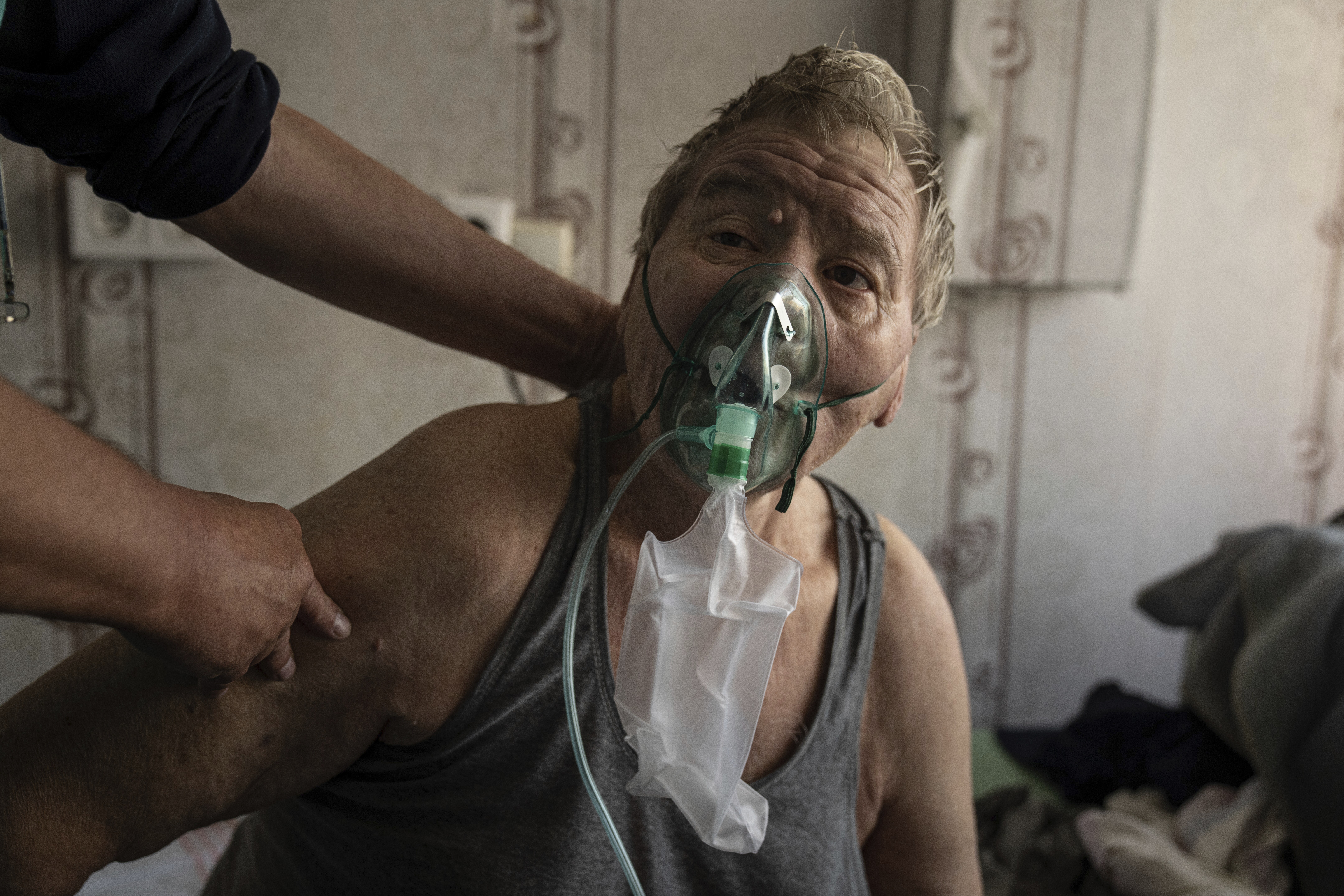 In this handout photo released by UNICEF, Valeriy, a patient with coronavirus, breathes with an oxy...