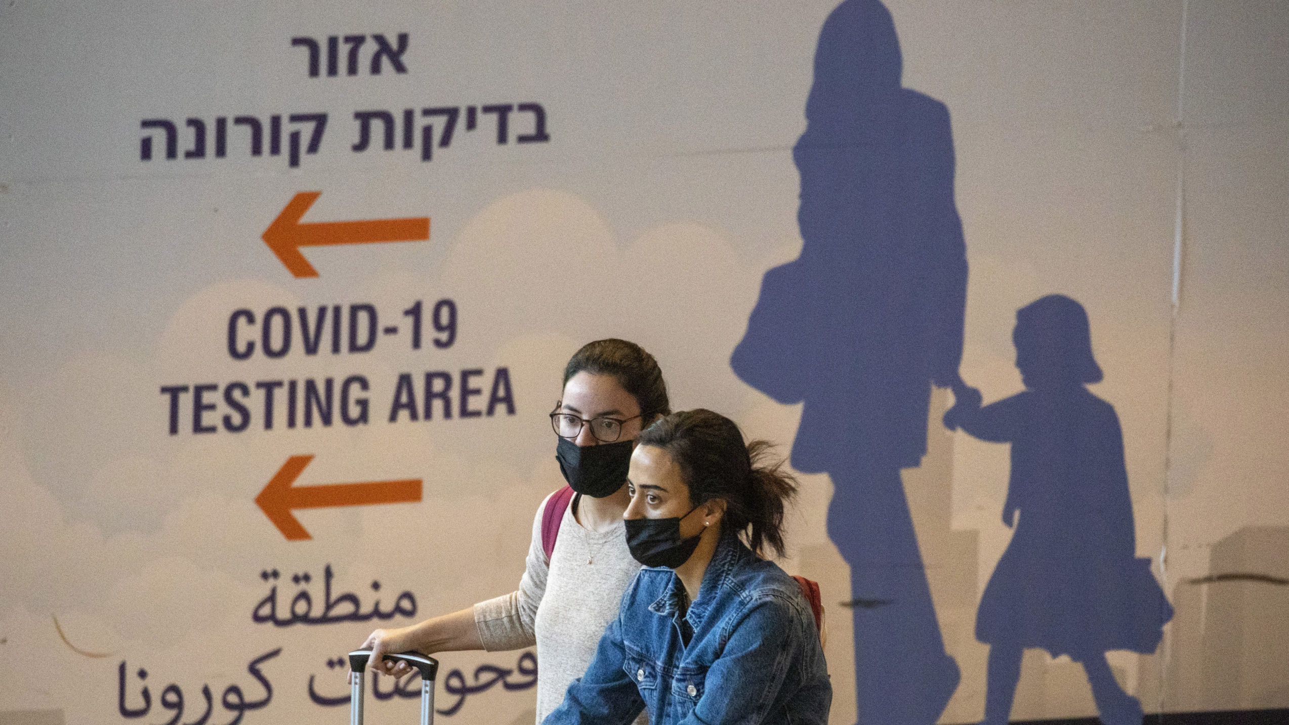Travelers wearing protective face masks arrive at Ben Gurion Airport near Tel Aviv, Israel, Sunday,...