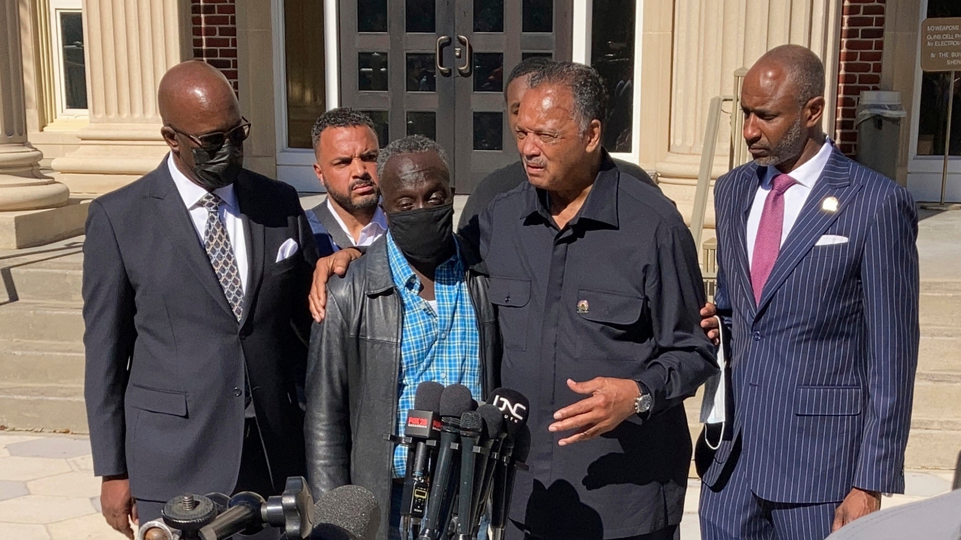 The Rev. Jesse Jackson, center right, puts his arm around Ahmaud Arbery's father, Marcus, in a news...